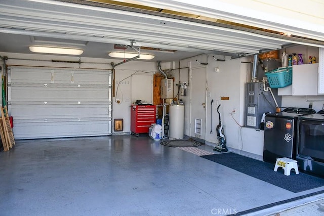 garage featuring water heater, washing machine and dryer, and a garage door opener