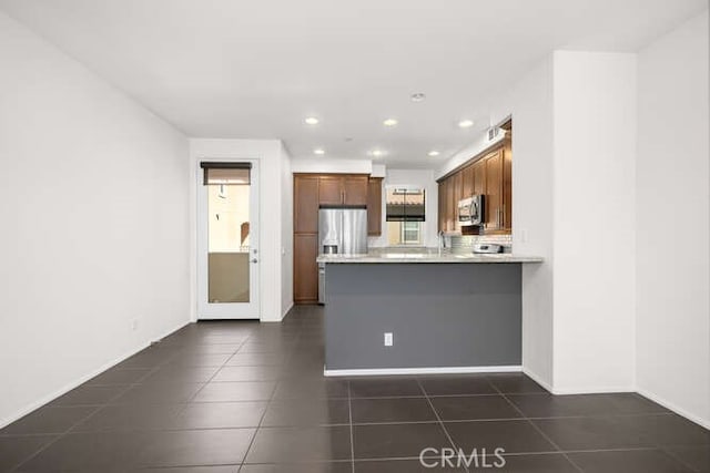 kitchen featuring dark tile patterned flooring, recessed lighting, stainless steel appliances, a peninsula, and light countertops