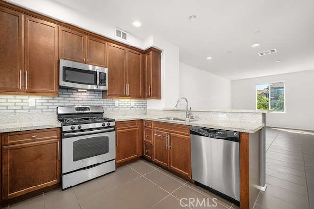 kitchen featuring visible vents, a peninsula, stainless steel appliances, and a sink