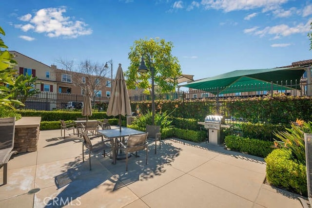 view of patio featuring outdoor dining area, a grill, and fence