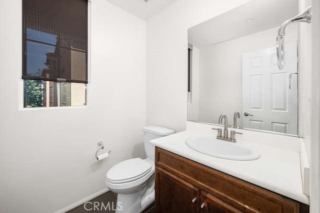 bathroom featuring baseboards, toilet, and vanity