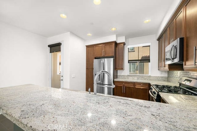 kitchen with a sink, stainless steel appliances, and light stone countertops