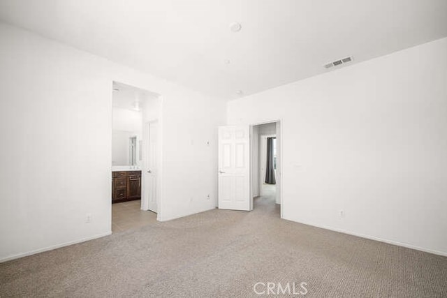 unfurnished bedroom featuring light colored carpet, visible vents, and connected bathroom