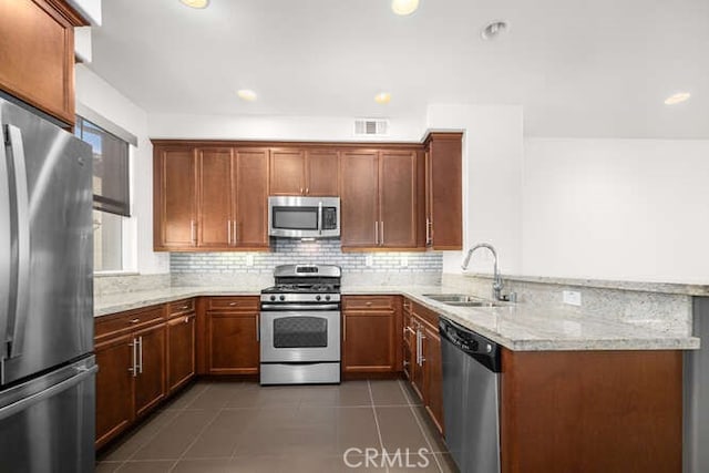 kitchen featuring visible vents, dark tile patterned flooring, a sink, appliances with stainless steel finishes, and a peninsula