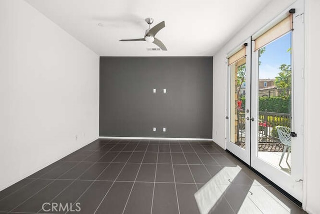 empty room featuring tile patterned flooring, visible vents, baseboards, and a ceiling fan