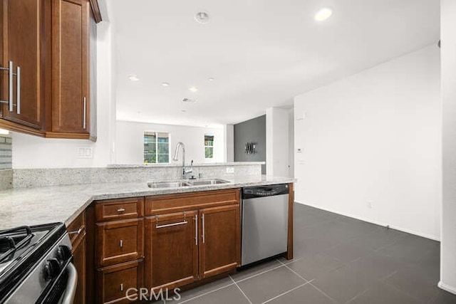 kitchen featuring light stone countertops, gas range, a peninsula, stainless steel dishwasher, and a sink