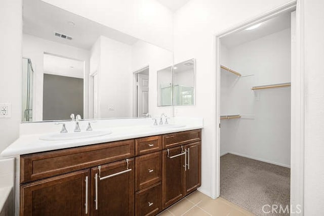 bathroom featuring a walk in closet, double vanity, visible vents, and a sink