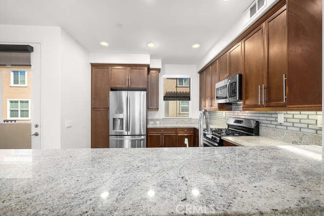 kitchen with visible vents, light stone counters, decorative backsplash, recessed lighting, and appliances with stainless steel finishes