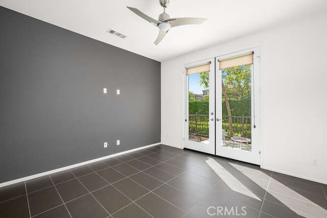 spare room with dark tile patterned flooring, baseboards, visible vents, and ceiling fan