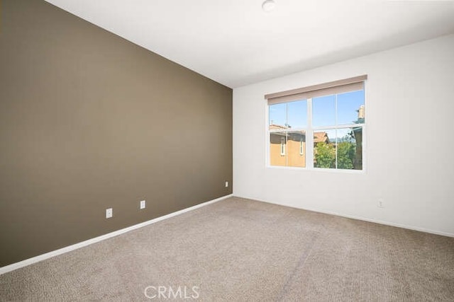 carpeted spare room featuring baseboards and lofted ceiling