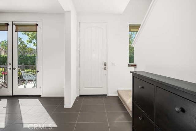 foyer entrance featuring dark tile patterned floors, french doors, and baseboards