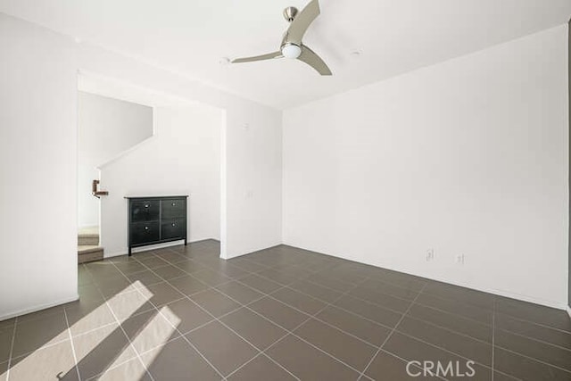 unfurnished living room featuring a ceiling fan and dark tile patterned flooring