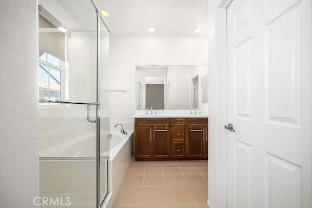 bathroom featuring tile patterned floors, a stall shower, double vanity, and a sink