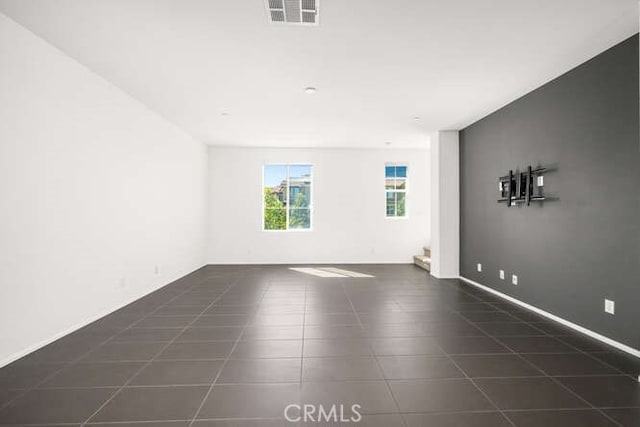 spare room with visible vents, baseboards, and dark tile patterned flooring