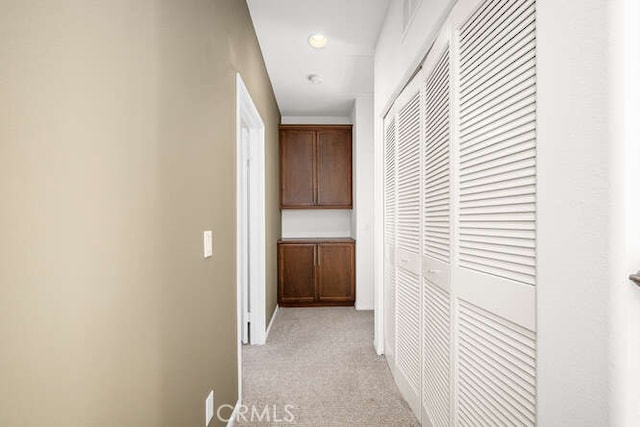 hall with baseboards and light carpet