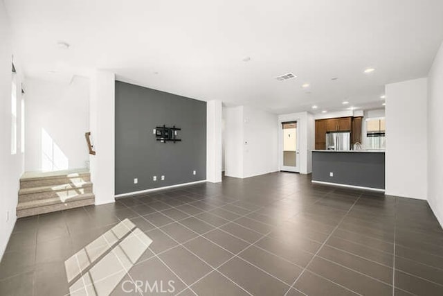 unfurnished living room featuring stairway, dark tile patterned floors, recessed lighting, and visible vents