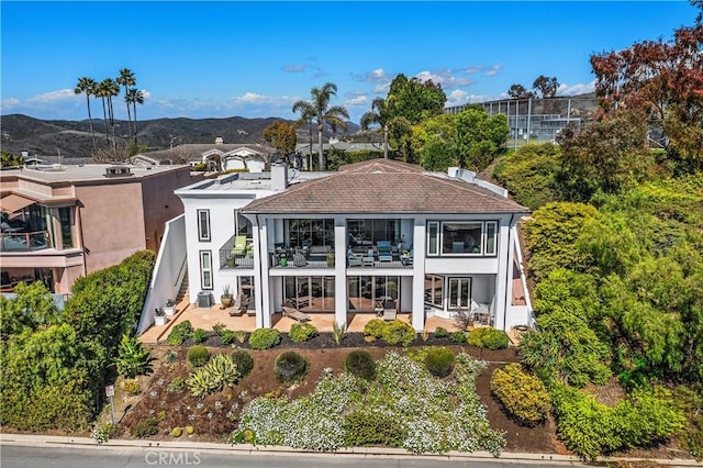 back of property with a balcony, stucco siding, stairs, a patio area, and a mountain view