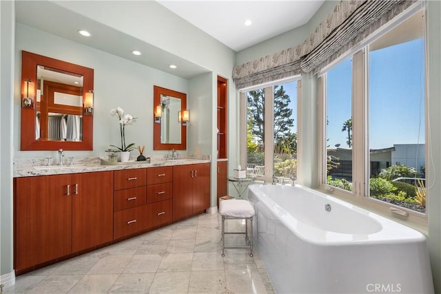 bathroom featuring a sink, double vanity, recessed lighting, and a tub