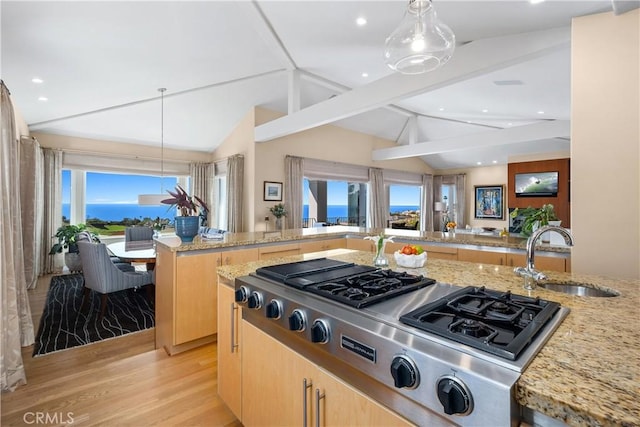 kitchen featuring lofted ceiling with beams, light stone counters, light brown cabinetry, and a sink