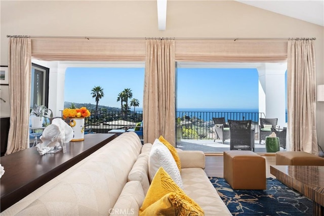 living area with lofted ceiling and a water view