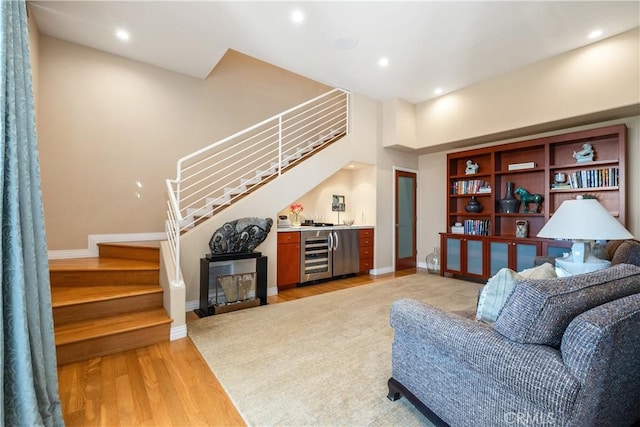 living room with wet bar, stairway, wine cooler, and light wood-type flooring