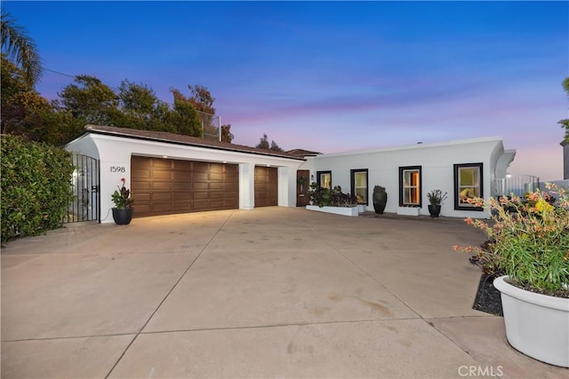 view of front of home with stucco siding, a garage, an outdoor structure, and concrete driveway