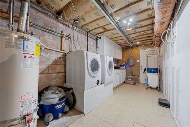 laundry area with cabinet space, concrete block wall, water heater, and washing machine and clothes dryer