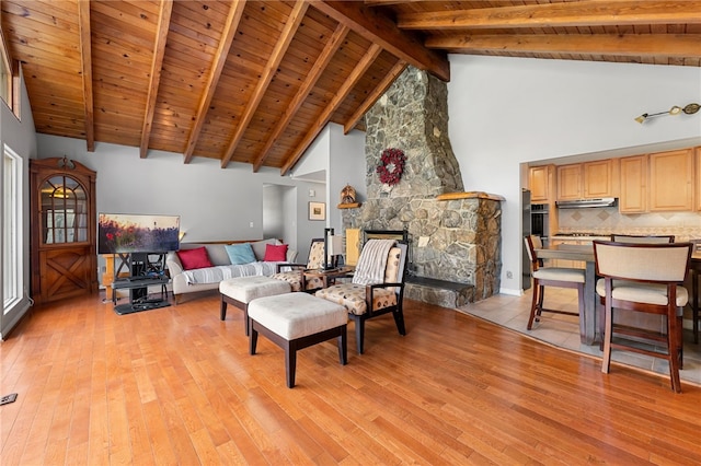 living area featuring a stone fireplace, wooden ceiling, beamed ceiling, and light wood finished floors