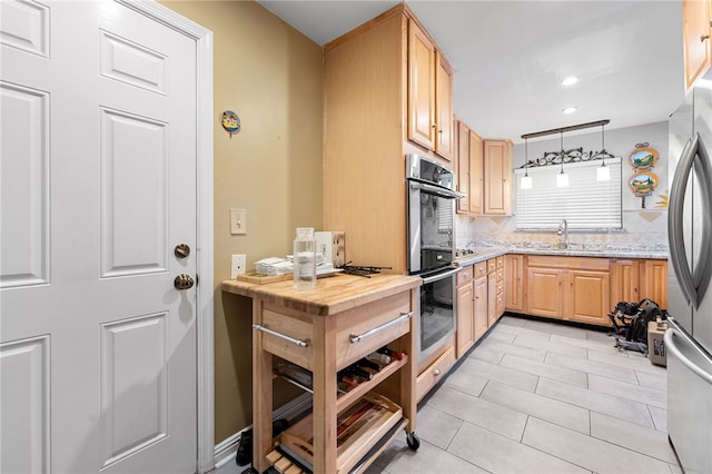 kitchen featuring backsplash, light brown cabinetry, light stone counters, stainless steel appliances, and a sink