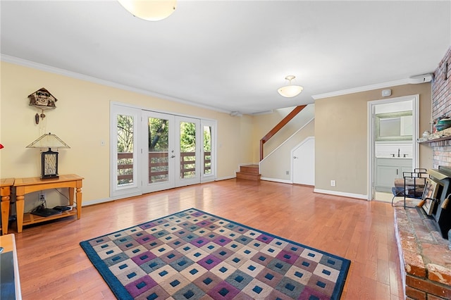 living room with baseboards, a fireplace, stairs, wood-type flooring, and crown molding