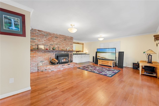 living room with crown molding, a wood stove, wood finished floors, and baseboards