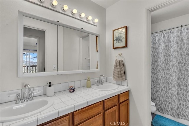 full bathroom featuring curtained shower, double vanity, toilet, and a sink