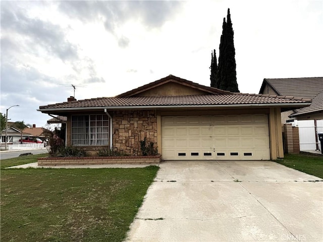 ranch-style house with a tile roof, concrete driveway, a front yard, a garage, and stone siding