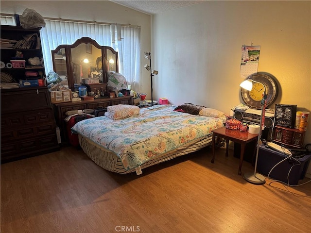 bedroom featuring a textured ceiling, wood finished floors, and vaulted ceiling