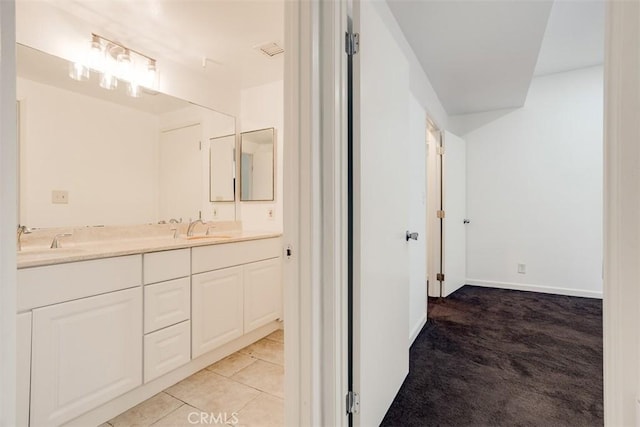 bathroom with a sink, baseboards, double vanity, and tile patterned floors