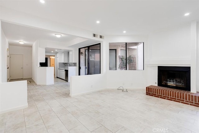 unfurnished living room featuring visible vents, recessed lighting, a fireplace, and baseboards