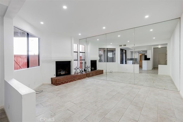 unfurnished living room with recessed lighting and a fireplace with raised hearth