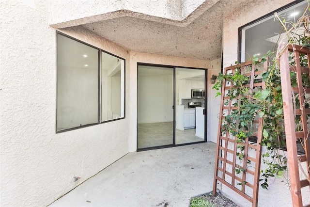 view of exterior entry featuring a patio and stucco siding