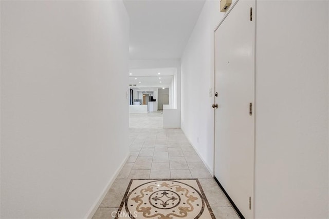 hallway with light tile patterned flooring and baseboards