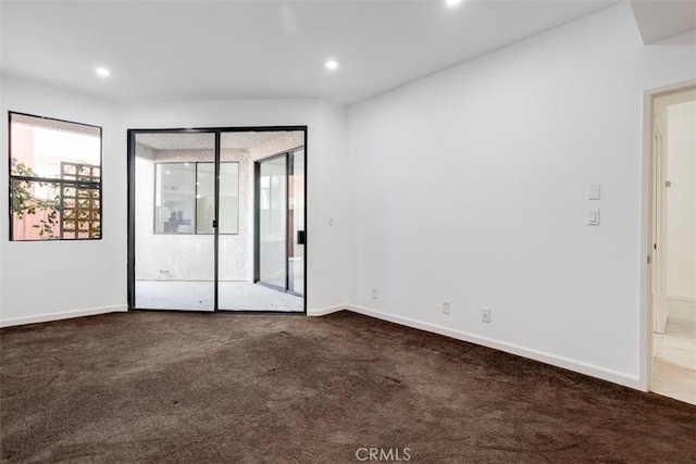 empty room with baseboards, a healthy amount of sunlight, and dark carpet