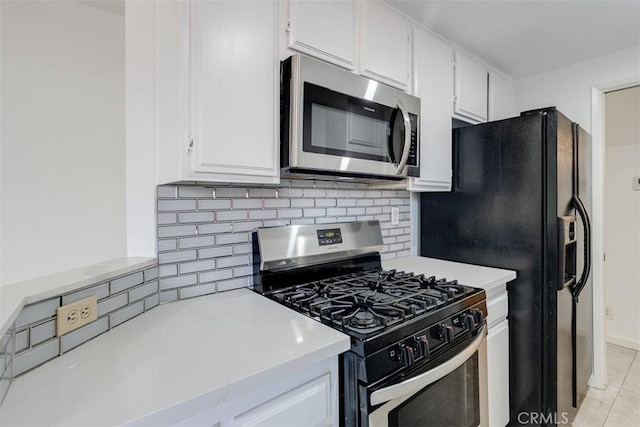 kitchen with light tile patterned floors, stainless steel appliances, light countertops, white cabinets, and backsplash