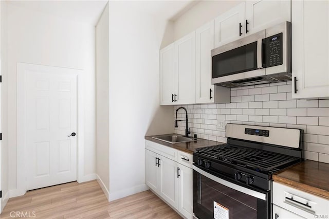 kitchen featuring dark countertops, light wood-style floors, appliances with stainless steel finishes, and a sink