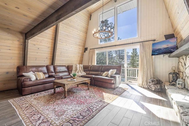 living area featuring beam ceiling, wooden walls, a notable chandelier, and wood finished floors