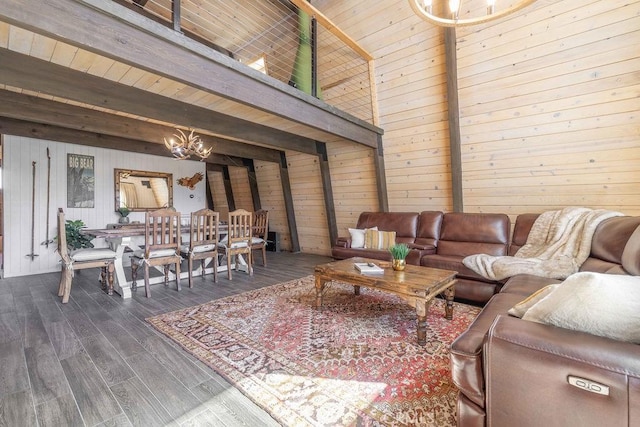 living area featuring dark wood finished floors, wooden walls, beamed ceiling, and an inviting chandelier