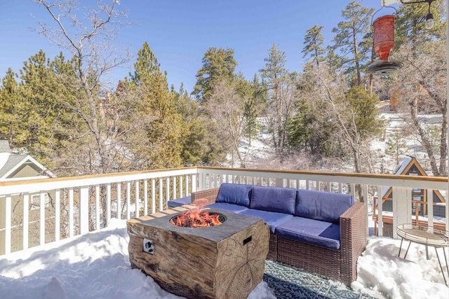 snow covered deck with an outdoor living space with a fire pit