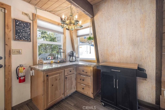 kitchen with light stone counters, dark wood-style flooring, beamed ceiling, dark cabinets, and a chandelier