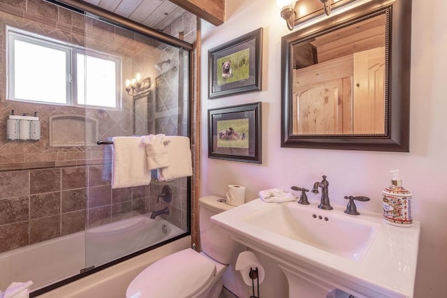 full bath featuring toilet, bath / shower combo with glass door, and a sink