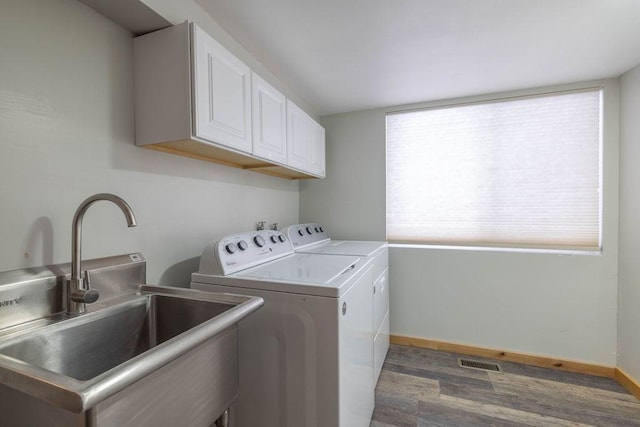 laundry area featuring visible vents, a sink, washing machine and dryer, cabinet space, and baseboards