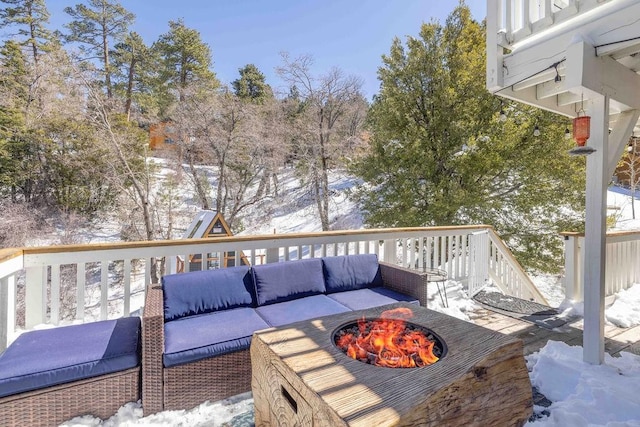 snow covered deck featuring an outdoor living space with a fire pit