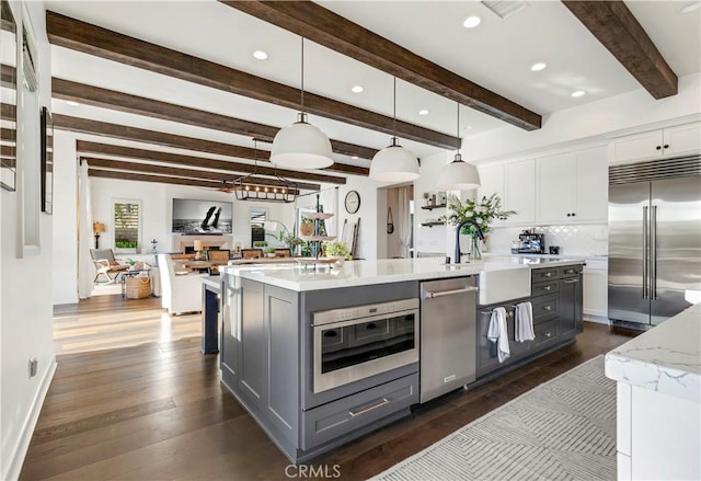 kitchen with gray cabinetry, a large island with sink, white cabinets, stainless steel appliances, and a sink